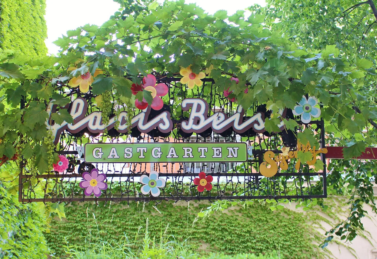 Bewachsenes Schild am Eingang zum Gastgarten des Glacis Beisl, einer der bekannten Gastgärten in Wien