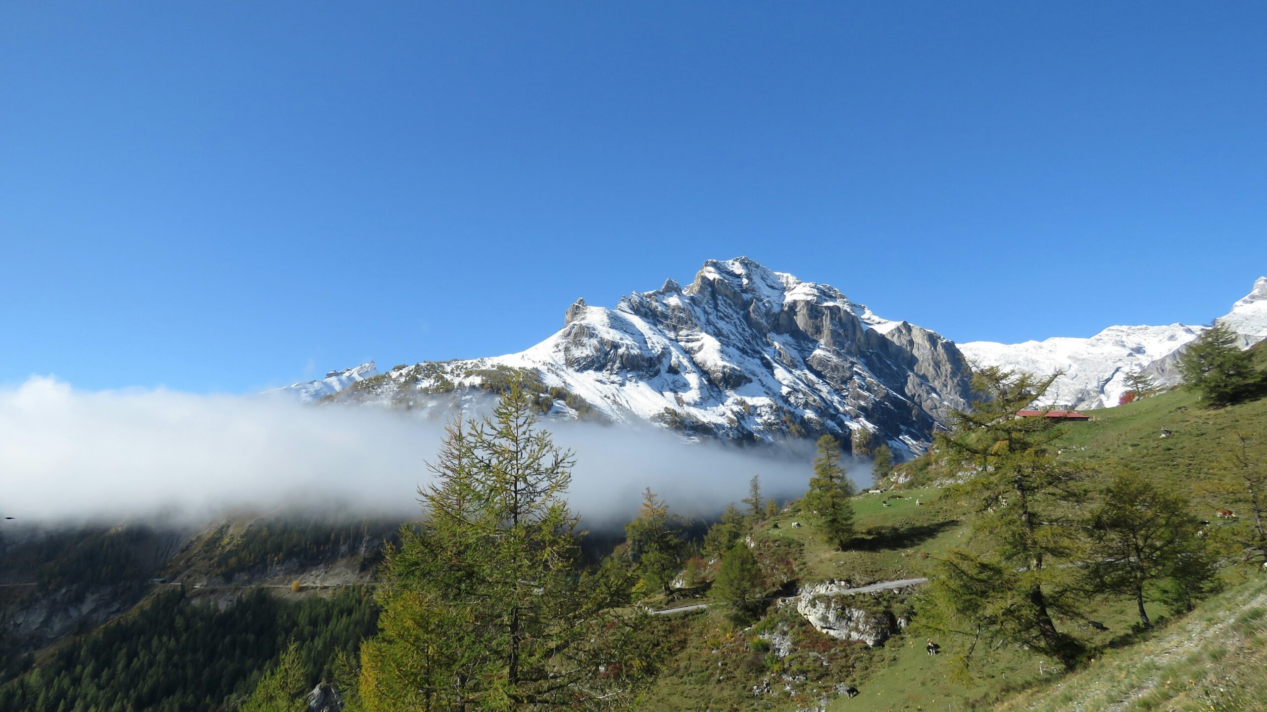 A mountain covered in snow and clouds with a blue sky