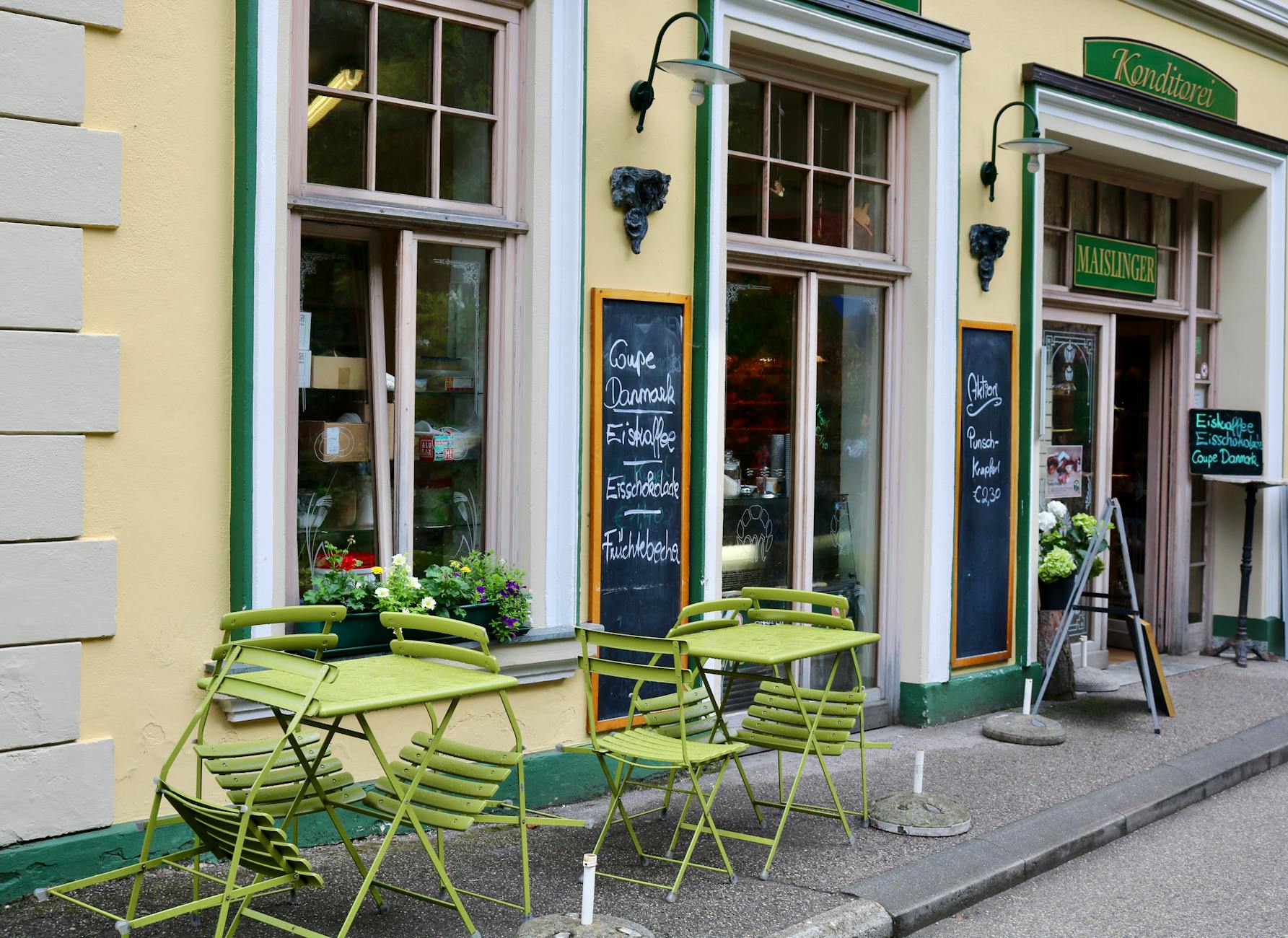 A picturesque Austrian café with green outdoor seating on a vibrant city street.