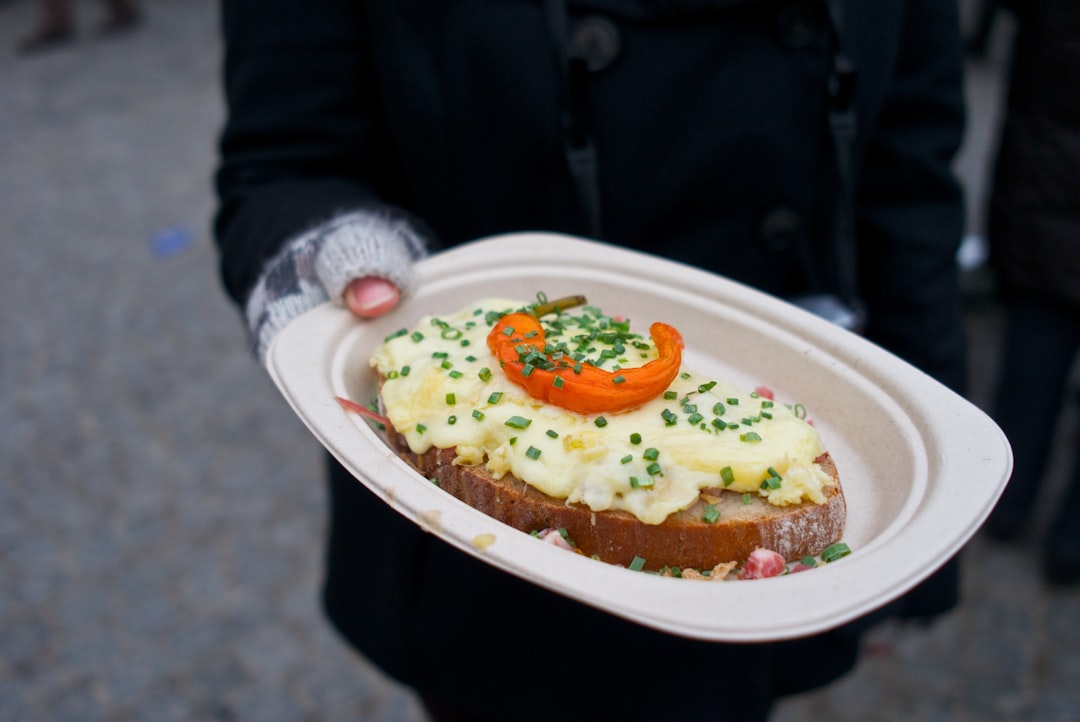 person holding white ceramic plate with orange and green food